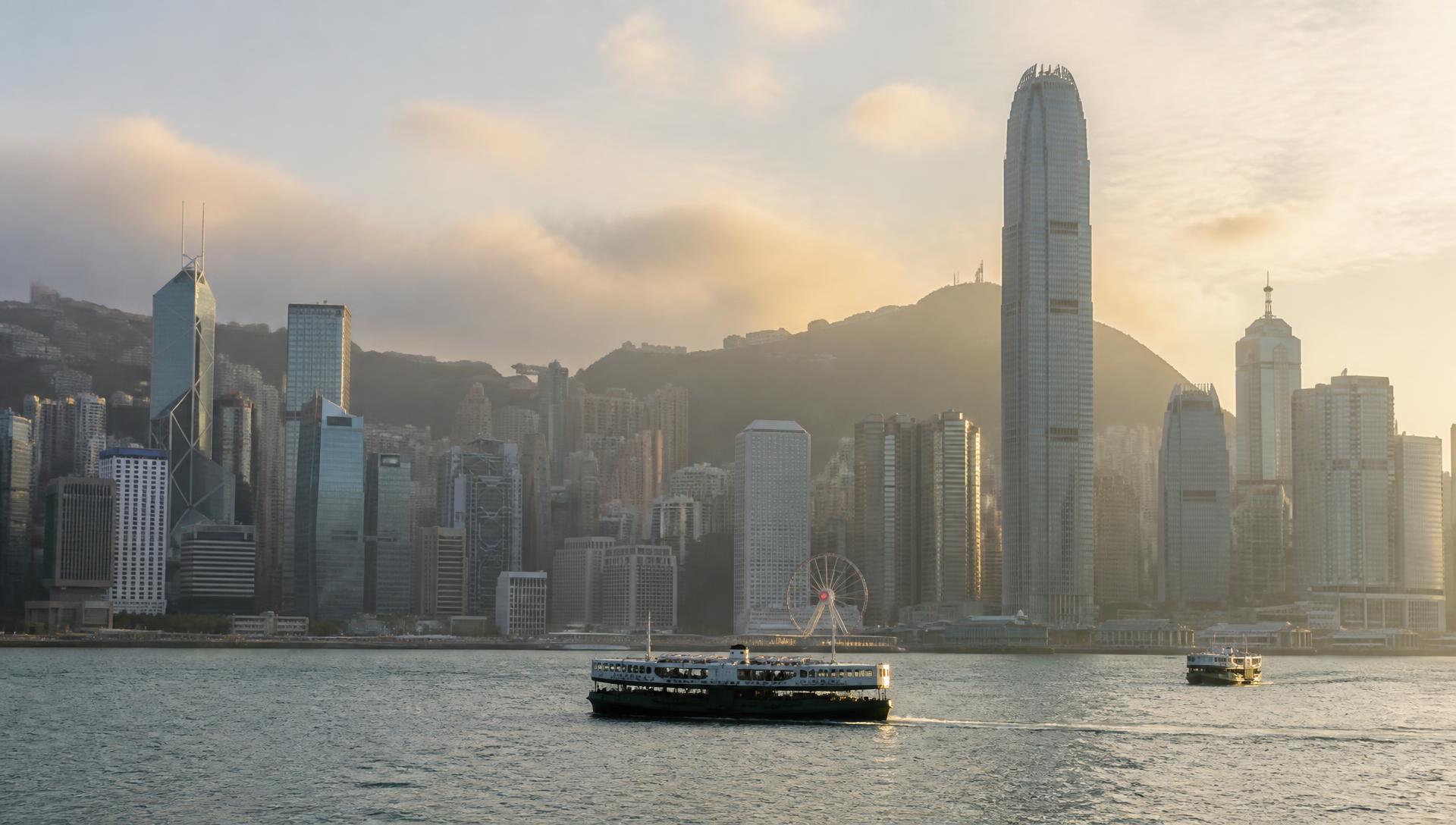 Star ferries crossing Victoria Harbour in Hong Kong at golden hour, with the city skyline and the Peak beyond